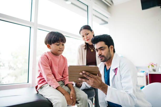 Boy, you see this video, very funny. Asian Indian doctor is playing with Malay little patient for making him happy before he is scare. general practitioner asian stock pictures, royalty-free photos & images