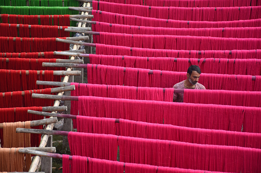 This picture documented men are working in a sari drying field in Shantipur. Shantipur is a small town in eastern India. It is known for its one of a kind handloom and power loom industries.