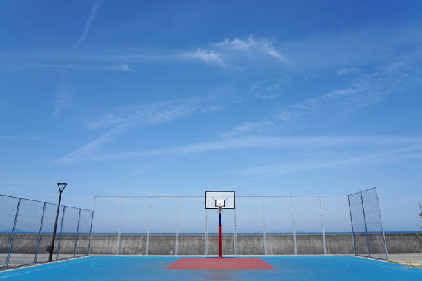 Basketball hoop on a blue sky Photos of basketball hoop on empty outdoor court on a blue sky. back board basketball stock pictures, royalty-free photos & images