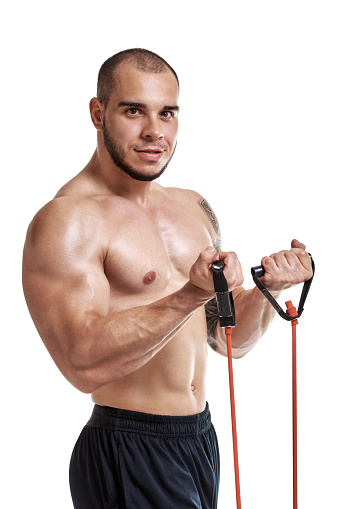Sporty muscular naked man exercising with elastic expander