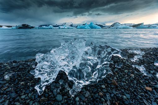 Moody landscape of Ice cracked on black beach and iceberg floating in Jokulsarlon glacier lagoon, Vatnajokull, Iceland