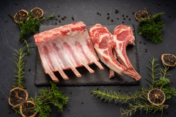 Fresh lamb rack with rosemary in black plate on wooden background, Fresh Raw lamb loin on black Background. Fresh lamb rack with rosemary in black plate on wooden background, Fresh Raw lamb loin on black Background. rack of lamb stock pictures, royalty-free photos & images