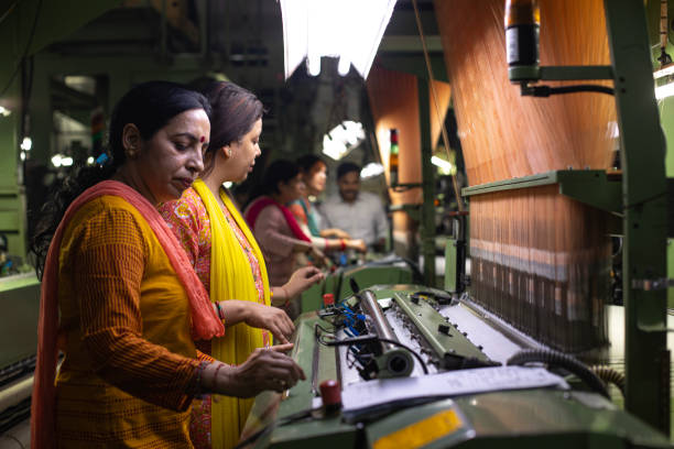 istock Female workers operating manufacturing equipment at textile factory 1493118424