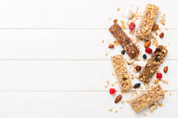 varias barras de granola sobre el fondo de la mesa. barras de granola de cereales. barritas de desayuno de superalimentos con avena, nueces y bayas, de cerca. concepto de superalimento - protein bar cereal oat cranberry fotografías e imágenes de stock