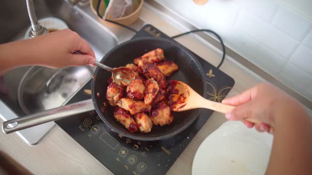 woman cooking fried chicken With Korean spicy sauce in the pan, happy eating and well being concept.
