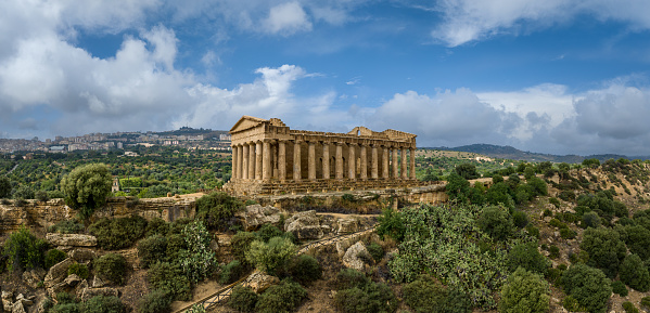 Temple of Concordia on hill top under blue summer skyscape. Aerial Drone Point of View Panorama at Valley of the Temples in Agrigento City. Stitched Mavic 3 Panorama Shot. Temple of Concordia, Valley of the Temples, Agrigento, Sicily Island, Southern Europe, Europe.