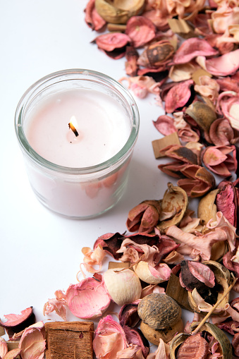 photo of a pink dried plant and a burning candle on a white background