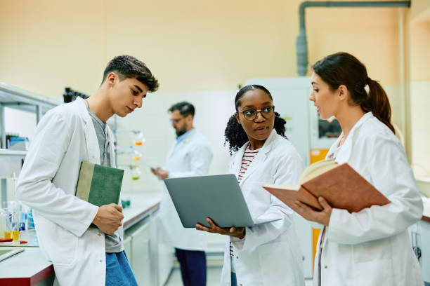 istock Black scientist and her coworkers talking while working on laptop in laboratory. 1493124828