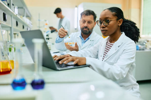 istock Black biochemist using laptop while working with colleague in laboratory. 1493124946