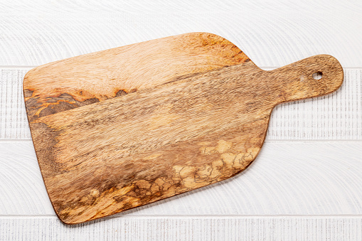 Wooden cutting board on white kitchen table. Flat lay with copy space