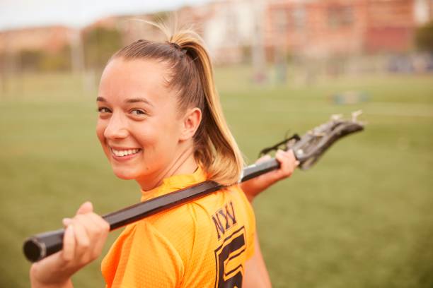 istock Confident Charm: Female Lacrosse Player's Headshot with Smiling Expression and Shoulder Resting Stick. 1493125235
