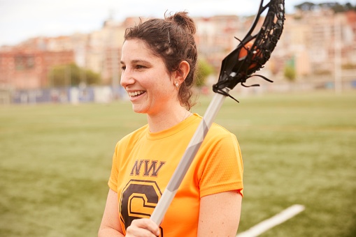 Candid shot of a Confident Lacrosse Player Showcasing Her Winning Smile with a Stick On her Shoulder