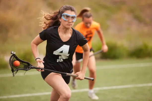 Photo of Speed and Pursuit: Lacrosse Player's Rapid Run as Rival Races to Close the Gap.