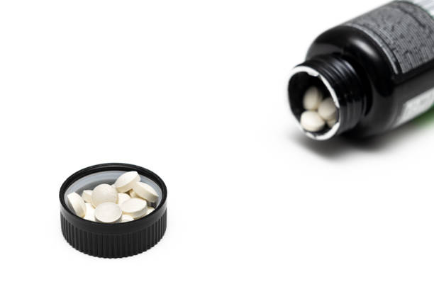 istock pills lie in a bottle cap on a white background. 1493133244