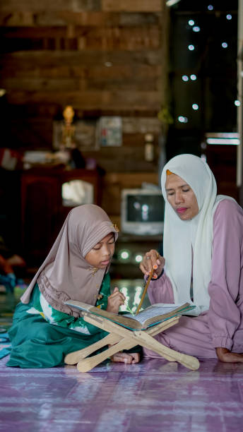 madre enseña a su hija a recitar el corán en casa - alquibla fotos fotografías e imágenes de stock