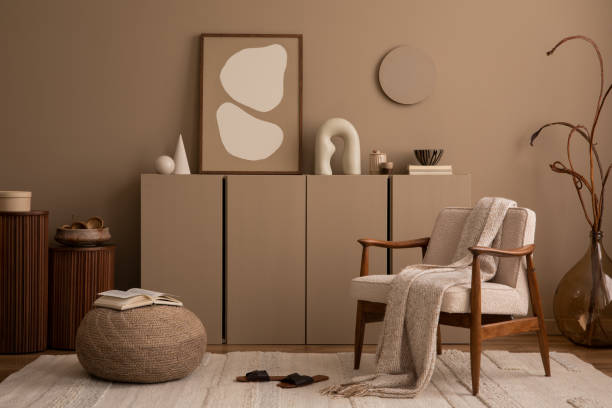 istock Aesthetics composition of living room interior with mock up poster frame, brown wall, sideboard, boucle armchair, sculpture, braided pouf, plaid and personal accessories. Home decor. Template. 1493136737