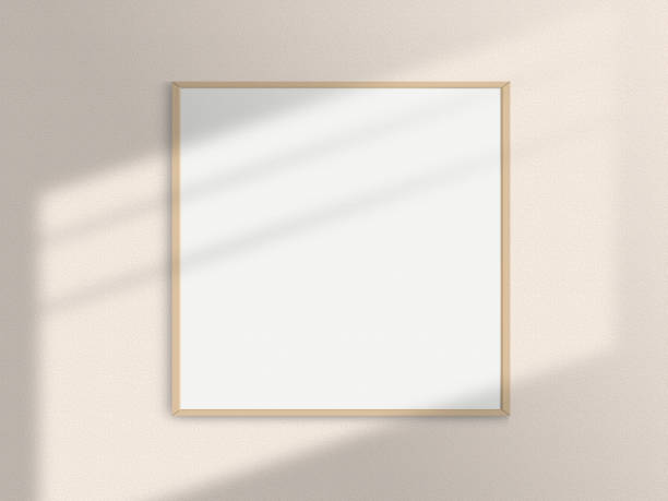 istock Realistic square photo frame mockup. Square wooden frame mockup on the wall with light window shadow overlay effect. Simple, clean, modern, minimal poster frame mock up. White picture frame mockup 1493142187