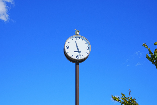 A clock installed outdoors with a refreshing blue sky in the background gives a positive image.