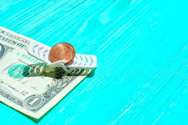 Penny resting on a toy beach lounger placed on top of a one-dollar bill, all set against a serene blue wooden background with copy space. Setting money aside for leisure and vacation expenses.