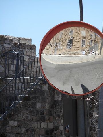 Round mirror shows the reflected distortion of city wall