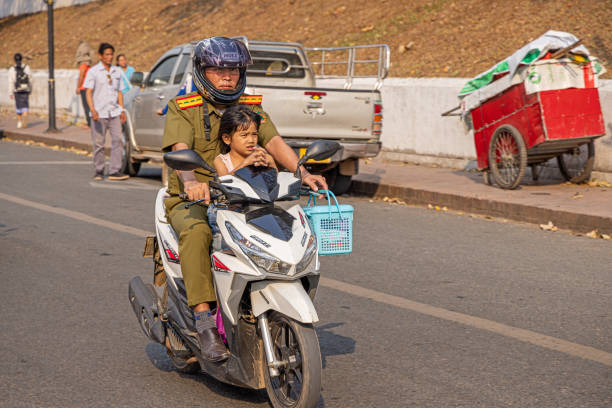 Luang Prabang, Laos - March 21th 2023: Father and daughter  driving down the street on a motorcycle
