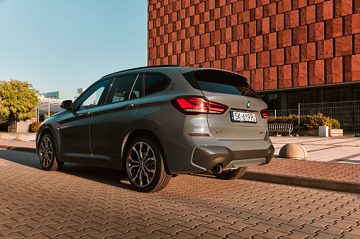 BMW X1 25e, hybrid, plug in car, parked next to a modern office building. The total power of both engines is 220HP. Electric range up to 52 km Katowice, Poland- 07.30.2021