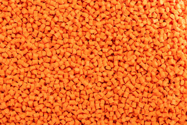 Close-up of orange plastic resin (Masterbatch) spread on a tray
