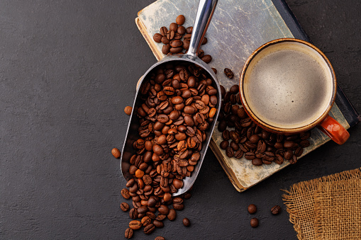 Rich coffee in a cup with aromatic roasted beans, a perfect morning brew. Flat lay with copy space