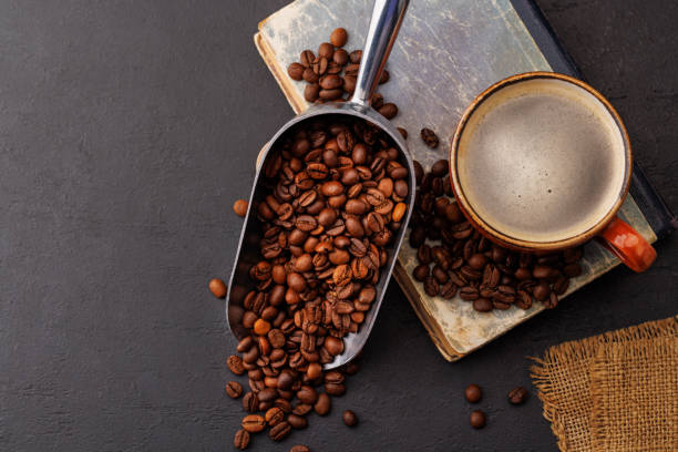 Rich coffee in a cup with aromatic roasted beans Rich coffee in a cup with aromatic roasted beans, a perfect morning brew. Flat lay with copy space roasted coffee bean stock pictures, royalty-free photos & images