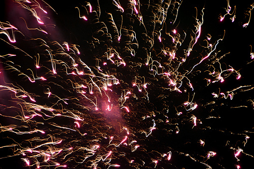 Celebration event: Fireworks in color neon, pink and red. Large group of wisps in the air.