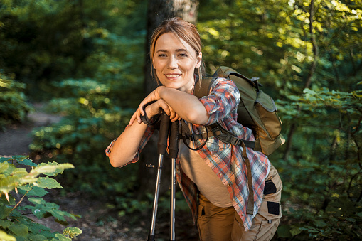 Female Hiker Leaning Her Head on Hiking Pole and Relaxing Surrounded by Nature During Holiday Vacation Trip