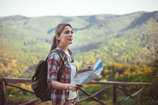 Hiking Woman Traveler With Backpack Checks Map to Find Directions in Wilderness Area, Real Explorer. Travel Concept