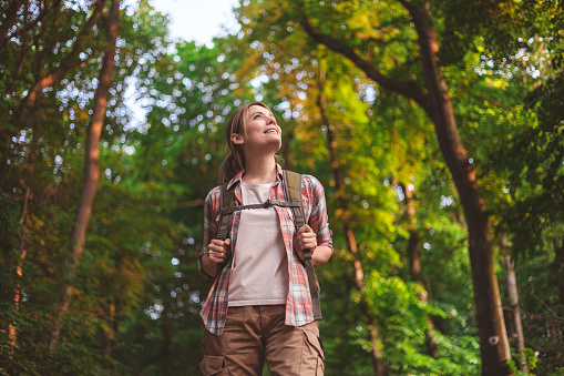 young woman walking in the middle of the forest enjoying the sun and nature.