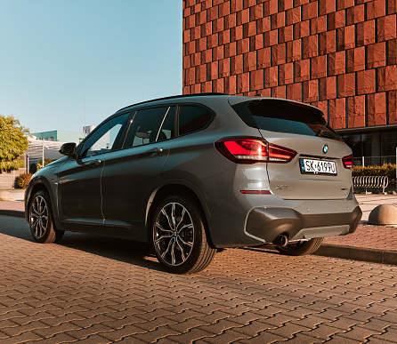 BMW X1 25e, hybrid, plug in car, parked next to a modern office building. The total power of both engines is 220HP. Electric range up to 52 km Katowice, Poland- 07.30.2021