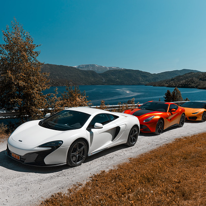 Road trip with supercars. Mclaren 650s, Ferrari F12 and Lamborghini Huracan parked on a gravel road by the lake. Gransherad, Norway. 04.06.2016