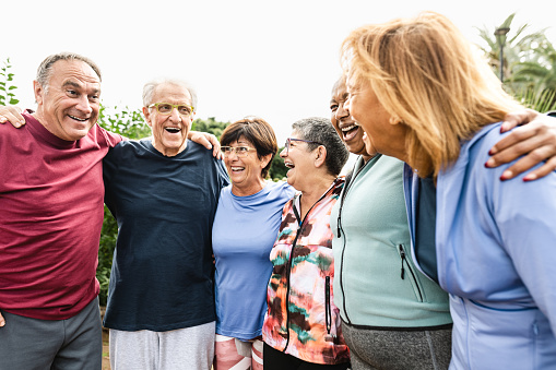 Group of diverse senior friends having fun after workout session at park