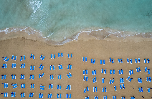 Drone aerial of beach chairs in a tropical sandy beach. Summer holidays in the sea. Protaras Cyprus Europe.