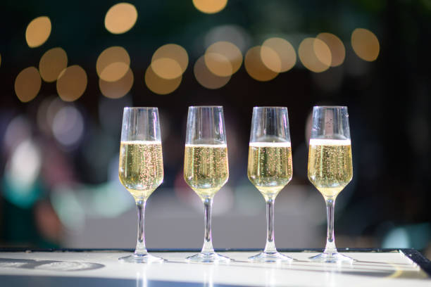 Sunny Champagne Flutes with champagne with defocussed string lights bokeh outdoors stock photo
