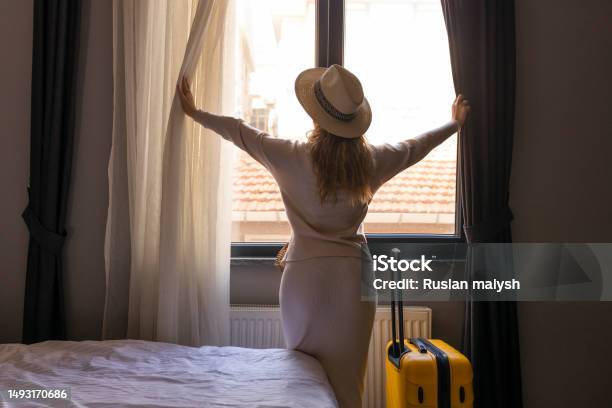 Portrait Of Tourist Woman Standing Nearly Window Looking To Beautiful View With Her Luggage In Hotel Bedroom After Checkin Stock Photo - Download Image Now