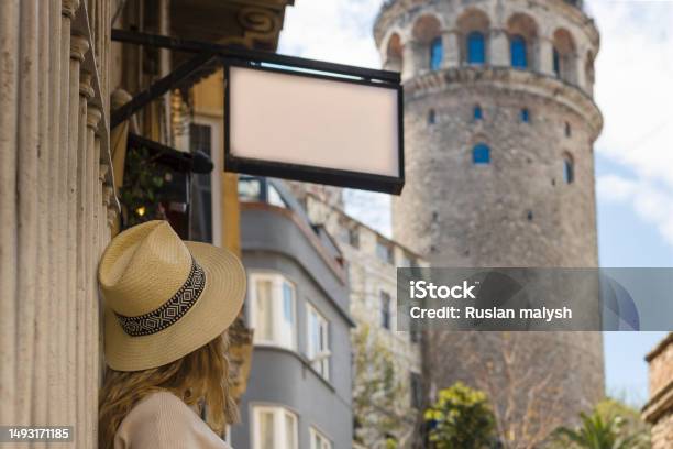 A Girl In A Hat Looks At The Galata Tower And Above It Hangs A Mockup With An Empty Space For The Logo Stock Photo - Download Image Now