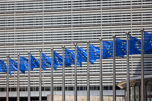 Brussels, Belgium - May 18, 2023: Blue flags of Europe in front of Berlaymont, seat of the European Commission. The building is located at the Robert Schuman Roundabout