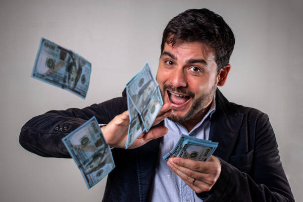 istock Smiling man throwing dollar bills into the air. 1493172370