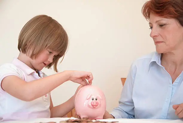 Photo of Daughter putting money in piggy bank