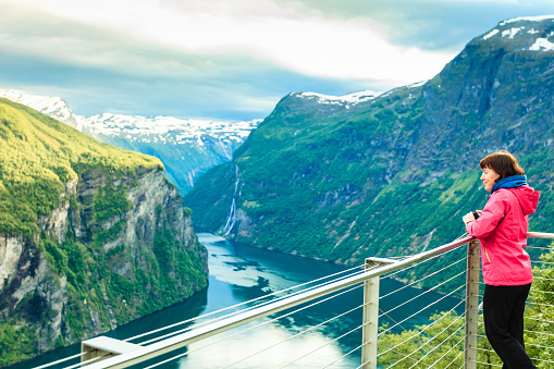 Tourism vacation and travel. Female tourist enjoying beautiful view over magical Geirangerfjorden from Flydalsjuvet viewpoint, Norway Scandinavia.