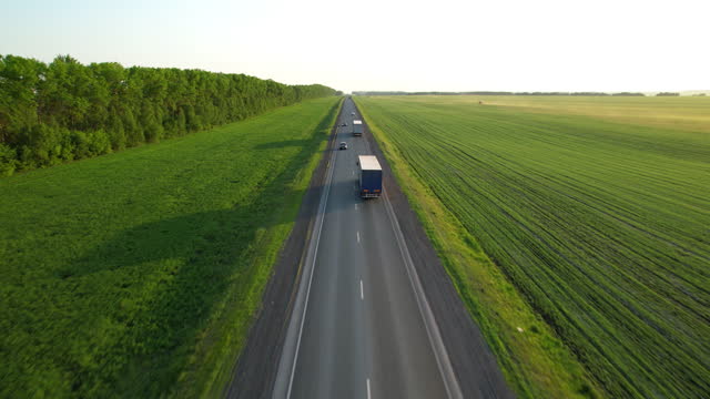 Trucks with a semi-trailer drive along the highway, aerial view.