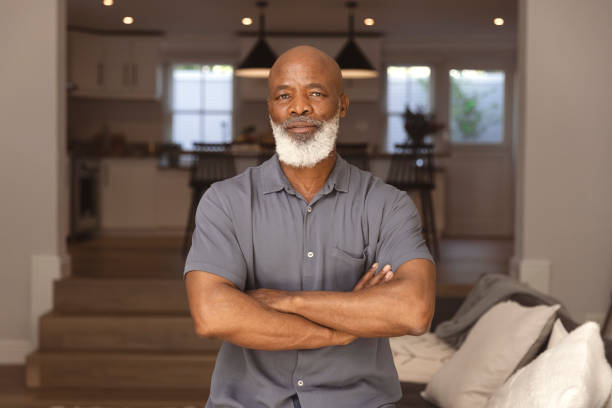 Portrait of a serious senior man at home Portrait of a serious senior man sitting on the sofa in his living room contemplating 60 69 years stock pictures, royalty-free photos & images