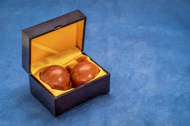 a pair of wooden Chinese medicine balls in a box on textured paper