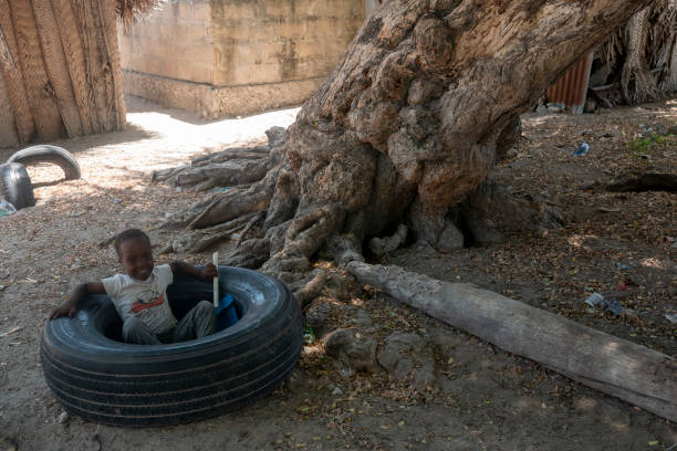 Zanzibar, Tanzania – 02.14.2023: Young boy plays in a rubber tire in Jambiani village