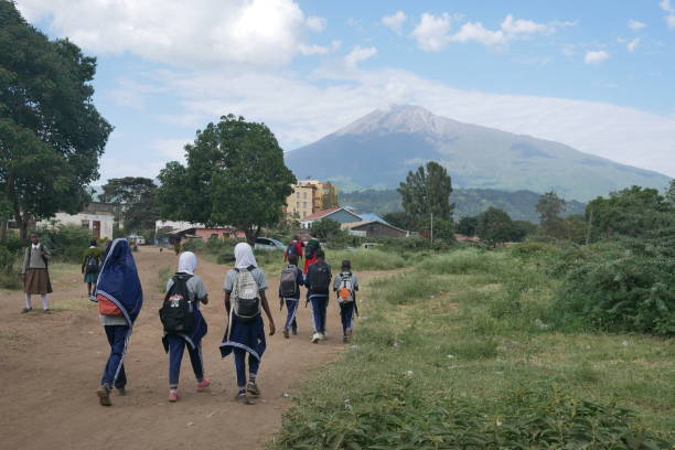 Schoolchildren walk home from school below Mount Meru stock photo