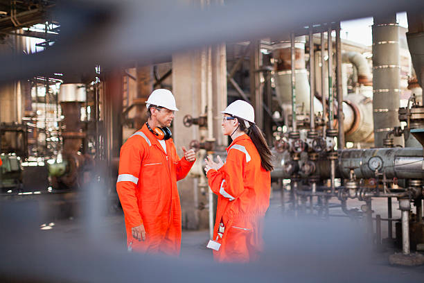 workers talking at oil refinery - โรงกลั่นน้ำมัน โรงกลั่น ภาพสต็อก ภาพถ่ายและรูปภาพปลอดค่าลิขสิทธิ์